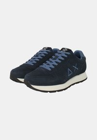 Scarpe da ginnastica blu navy in materiale scamosciato, con lacci e dettagli azzurri. Suola intermedia bianca e suola in gomma con un logo triangolare.