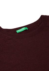 Burgundowy sweter z ryflowanym okrągłym dekoltem i miękką teksturą. Posiada zieloną metkę z napisem "United Colors of Benetton."
