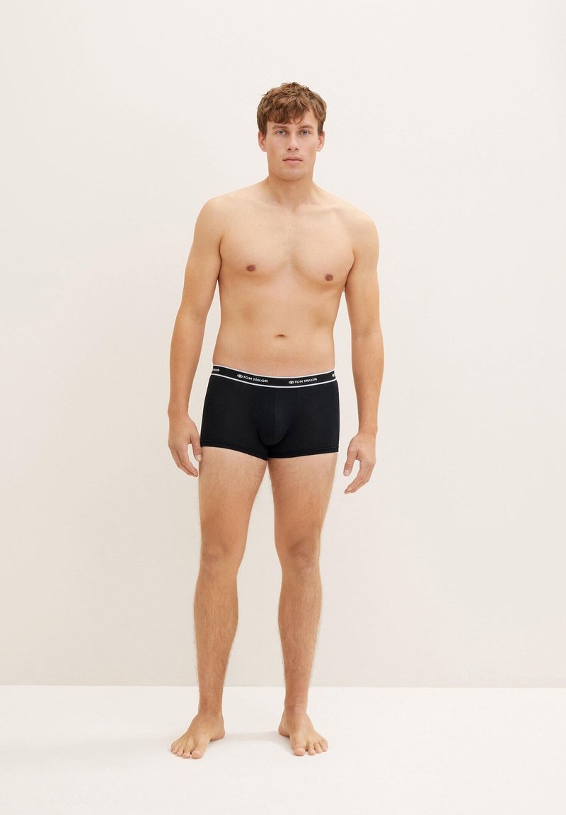 Svarta bomullshorts med en åtsittande design, med en kontrasterande midjeband och minimal branding. Modellen visar framifrån.