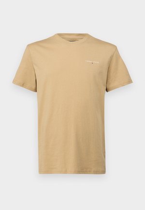 T-shirt de algodão em bege claro, com decote redondo, mangas curtas, apresentando um pequeno logotipo "Tommy Jeans" em branco no peito. Textura suave.