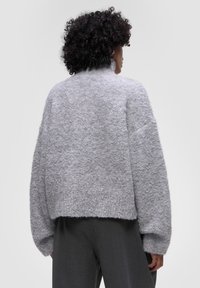 Šedý svetr s texturovaným, chlupatým úpletem; zkrácený design, spadlé ramena a široké rukávy. Kombinujte s kalhotami s vysokým pasem pro ležérní vzhled.