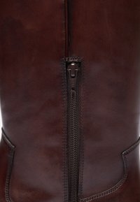 Botte en cuir marron montante avec zip sur le côté, texture lisse et détails de couture subtils.