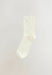 Chaussette en coton couleur crème, design côtelé, longueur mi-mollet, texture lisse, avec un bout arrondi et un talon renforcé.