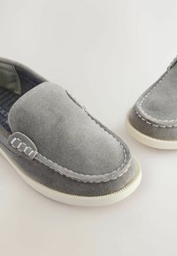 Graue Wildleder-Slipper mit weißen Nähten und strukturierten Akzenten, runde Spitze und cremefarbener Gummisohle.