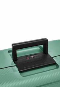 Maleta verde menta con una superficie texturizada, que presenta un mango negro y cerraduras de combinación integradas. Diseño de material suave y duradero.
