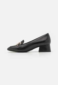 Black leather pump with a pointed toe, small block heel, and a decorative gold-toned hardware detail on the upper. Smooth texture.