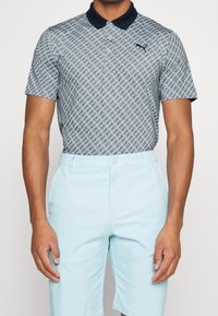 Ljusblå pikétröja med diamantmönster, har en marinblå krage och logotyp. Kombinerad med ljusblå shorts, slät textur, skräddarsydd passform.