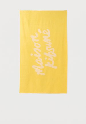 Prosop galben dreptunghiular cu textul "maison kitsuné" scris diagonal cu un font cursiv roz deschis.