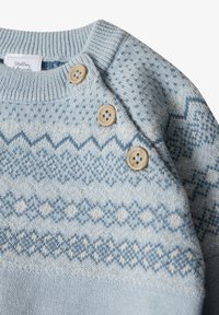 Hellblauer Strickpullover mit geometrischem Muster, geripptem Ausschnitt und drei Holzknöpfen an der Schulter. Weicher Stoff.