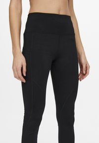 Leggings sportivi neri con vita alta, design elegante, cuciture piatte e tasche laterali, realizzati in materiale elastico e traspirante.