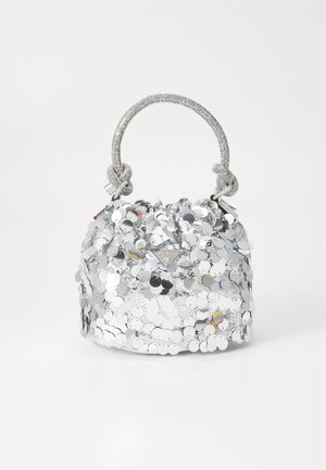 Kleine silberne Handtasche, bedeckt mit Pailletten, mit einem geflochtenen Griff, der in Knoten gebunden ist, und einem metallischen Guess-Logo vorne.