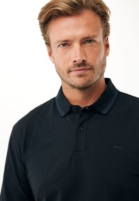 Polo shirt di un blu scuro con un colletto a coste e dettagli blu, caratterizzato da un'apertura con due bottoni e un logo discreto sul petto. Tessuto liscio.