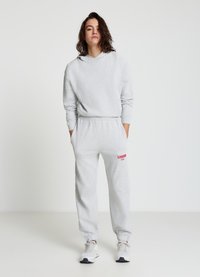 Sweat à capuche gris avec cordon de serrage et pantalon de survêtement assorti portant l'inscription "LONDON 1900" en rouge. Le matériau semble doux, avec des poignets et des détails aux chevilles côtelés.