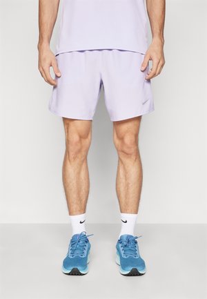 Vaaleanvioletit urheilushortsit, joissa on joustava vyötärönauha, yhdistettyinä sinisiin juoksukenkiin ja valkoisiin sukkiin, joissa on musta Nike-logo.