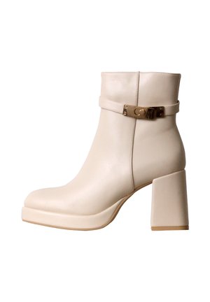Bottine beige en cuir avec talon haut épais et bride décorative à boucle dorée autour de la partie supérieure.