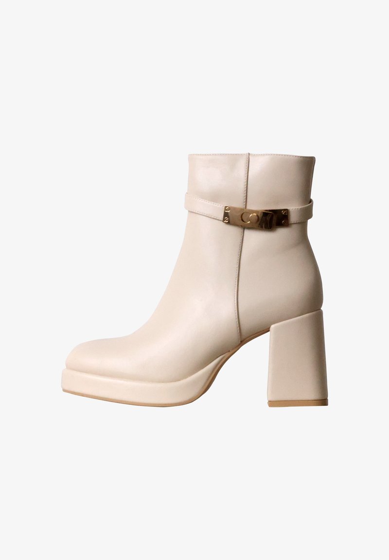 Bottine beige en cuir avec talon haut épais et bride décorative à boucle dorée autour de la partie supérieure.