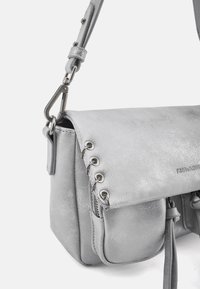 Borsa a tracolla in pelle argentata con patta magnetica, occhielli decorativi in metallo e tasca con zip. Dotata di tracolla staccabile e finitura testurizzata.