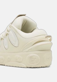 Cremefärgade sneakers med strukturerad ovandel, vadderad krage och präglad logotyp på hälen. Tjock sula med mönstrad detalj.