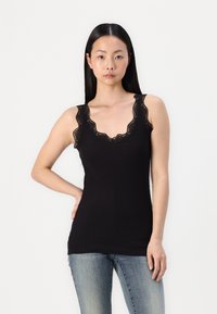 Top negro sin mangas con un escote de encaje en punta y tirantes anchos, hecho de una tela suave. Combinado con jeans de color azul claro.