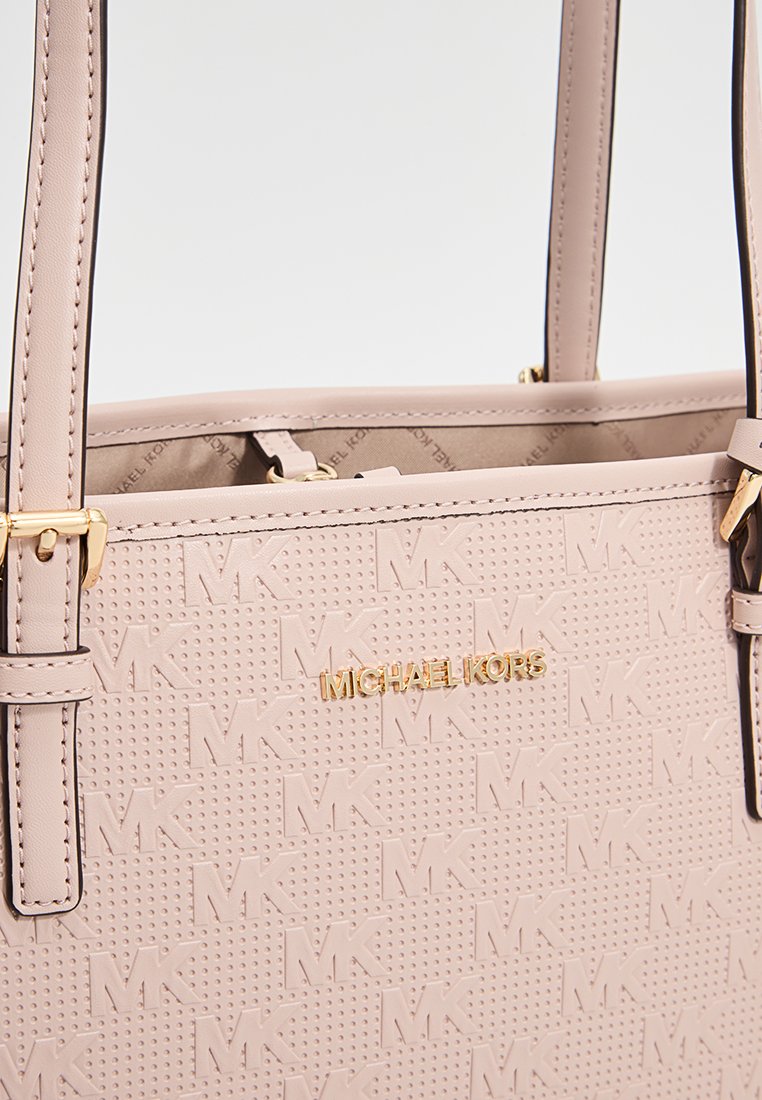 Bolso tote de Michael Kors en color rosa claro con superficie texturizada, logo dorado y asas dobles. Presenta un diseño minimalista con detalles de marca sutiles.