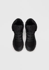 Black high-top boots featuring a textured upper, stitched accents, and thick rubber sole. Laces made of woven material for added grip.