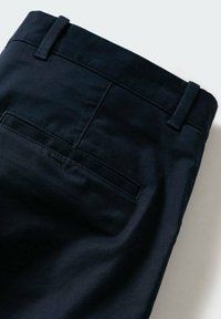 Pantalon sur mesure bleu marine foncé montrant une poche arrière et des passants de ceinture sur un fond clair.