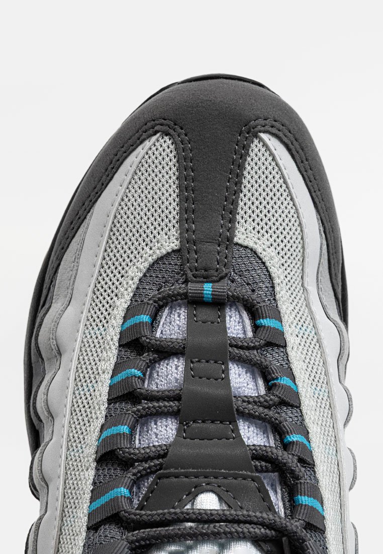 Zapatilla con empeine de malla gris, acentos negros y detalles azules. Presenta una lengüeta acolchada y cordones texturizados para un ajuste seguro.
