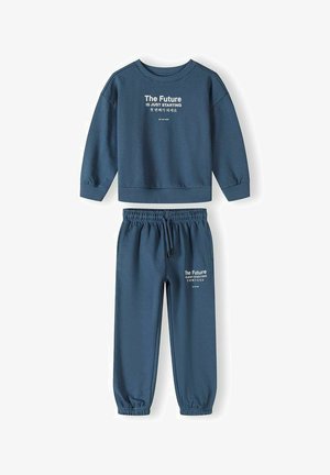 Kék hosszú ujjú pulóver és melegítőnadrág szett rugalmas mandzsettával, angol és koreai nyelvű "The Future IS JUST STARTING" felirattal a felsőn és a nadrágon.