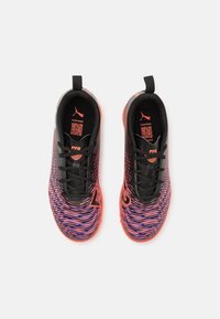 Baskets de sport noires et orange avec un motif ondulé multicolore. Elles présentent un matériau texturé, un design à lacets et une languette à l'arrière.