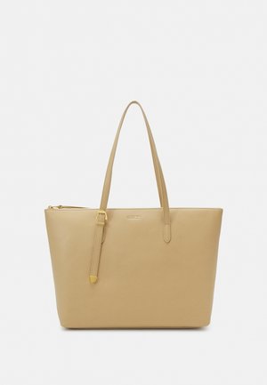 Sac cabas en cuir beige avec deux fines bretelles, dont une ajustable avec une boucle dorée, et une fermeture éclair sur le dessus.