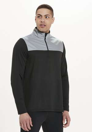 Schwarzer Pullover mit langen Ärmeln, der ein graues Panel über der Brust hat, einen halben Reißverschluss am Kragen und einen glatten Stoff. Hat einen lockeren Schnitt.