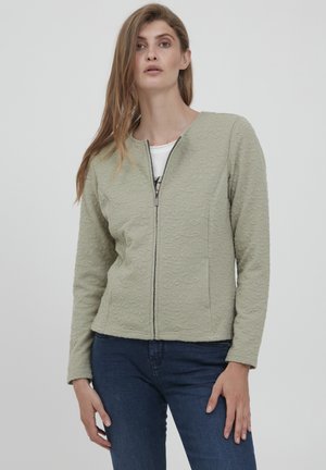 Ljusgrön zip-up jacka med texturerad tyg, rund halsringning och strukturerad passform. Passar bra med denim för en avslappnad look.