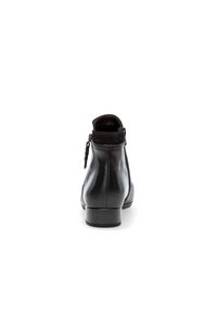 Botín de cuero negro hasta el tobillo con un acabado suave, cremallera lateral y tacón bajo. Los acentos de ante en el collar añaden textura.