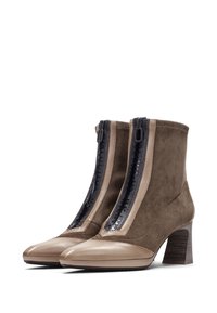 Botas de tobillo de ante marrón con puntera de cuero brillante color marrón claro, que presentan un cierre de cremallera negra y un tacón de bloque texturizado.