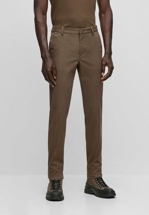 Pantalons fins marron en tissu texturé, avec une taille plate, des passants de ceinture et des poches latérales, associés à des chaussures à lacets noires.