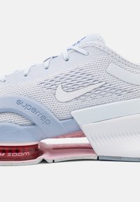 La zapatilla de entrenamiento Nike Superrep cuenta con una parte superior de malla azul claro, acentos blancos y una unidad de amortiguación de aire roja visible en la suela.