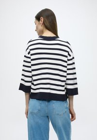 Stripet genser i marineblått og hvitt bomull, 3/4-ermer, avslappet passform, ribbet nederkant, og bakside som viser lysvasket denimjeans.