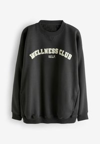 Musta dressipluus lõdva lõikega, millel on koorikvärvi kirja "WELLNESS CLUB" ja "SELF.", soonikkoes varrukasuunad ja ümar kaelus.