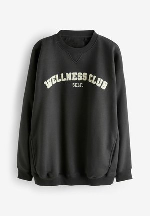 Black sweatshirt with a relaxed fit, featuring "WELLNESS CLUB" and "SELF." in cream-colored lettering, ribbed cuffs, and a round neckline.