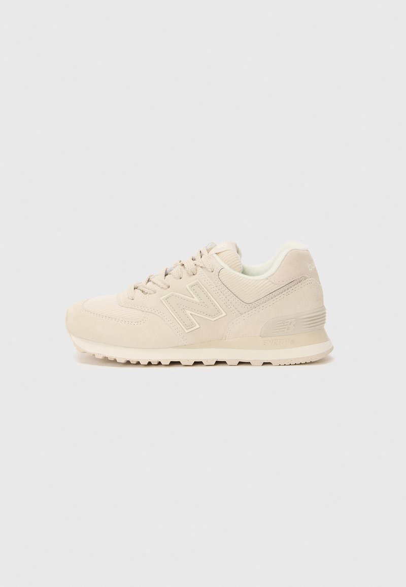 Beige New Balance sneaker with suede and mesh upper, lace-up closure, padded collar, and textured rubber sole on a white background.