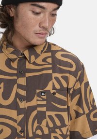 Korte mouwen shirt in bruin en tan met een gedurfde abstracte print, een button-down kraag, borstzak en een merklogo patch.