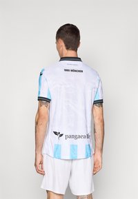 Balta futbolo marškinėliai su šviesiai mėlynais akcentais ir juodu apykakle. Ant nugaros užrašyta "1860 MÜNCHEN", o apačioje priekyje yra logotipas.