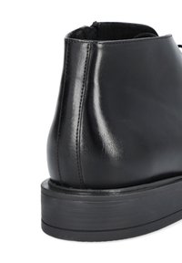 Czarne skórzane botki na kostkę o eleganckim wzornictwie, gładkiej fakturze i grubym gumowym spodzie, z widocznymi szwami w okolicy pięty.
