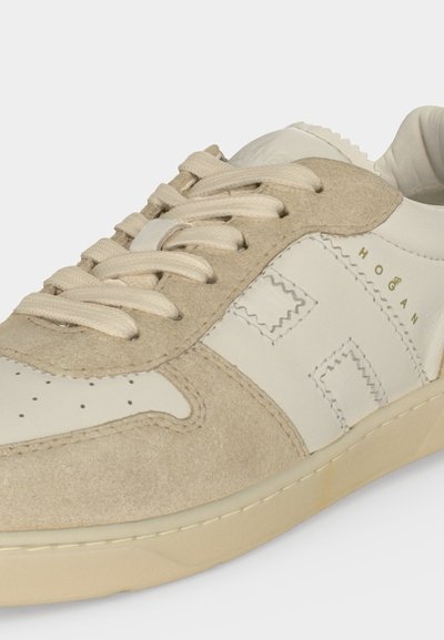 Baskets beiges et blanc cassé à lacets avec panneaux en daim et cuir, bout perforé, design cousu et logo "Hogan" sur le côté.