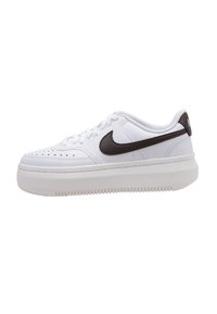 Zapatillas deportivas blancas con una superficie texturizada, que presentan un swoosh de Nike marrón, un diseño de cordones y una suela gruesa blanca.