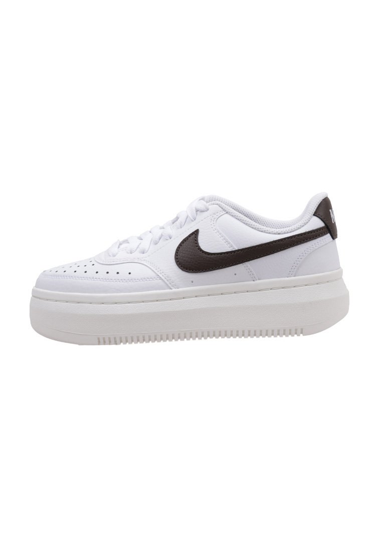 Zapatillas deportivas blancas con una superficie texturizada, que presentan un swoosh de Nike marrón, un diseño de cordones y una suela gruesa blanca.