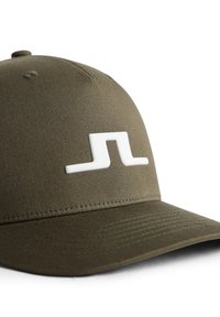 Olivgrön keps av tyg med böjd skärm. Har en stor vit logotyp på framsidan och texturerade ytdetaljer.