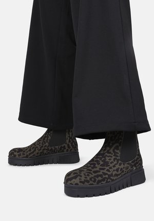 Stivali alla caviglia con stampa leopardata, pannelli laterali elastici neri, suole in gomma e un design con piattaforma spessa, abbinati a pantaloni neri a gamba larga.