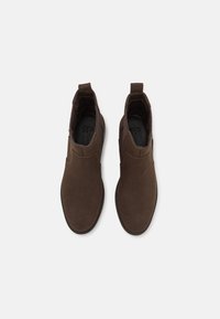 Brune semskede ankelstøvler med elastiske sidepaneler, grebslister og en struktureret gummisål. Glat overflade med en rund tådesign.