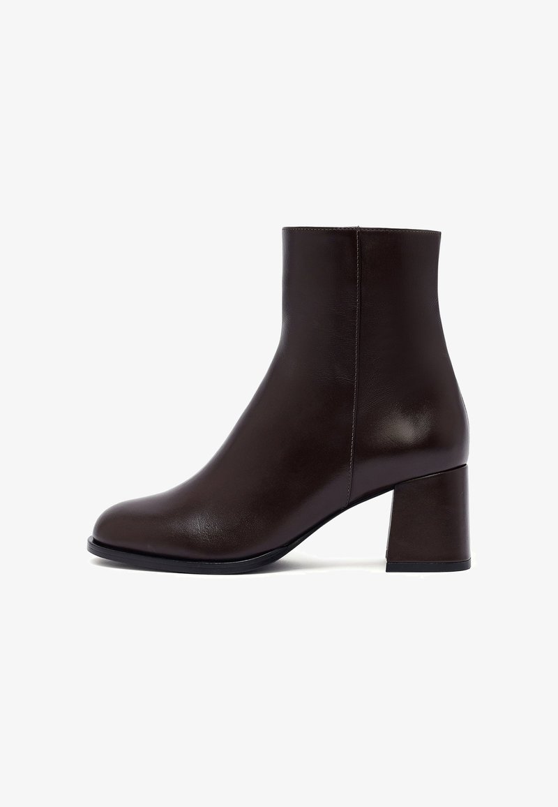 Bottine en cuir marron avec un bout rond et un talon carré, présentant une texture lisse et un design minimaliste. Aucun matériel ou détail visible.
